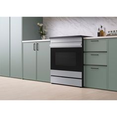 a black and silver oven in a kitchen with white counter tops, green cabinets and drawers