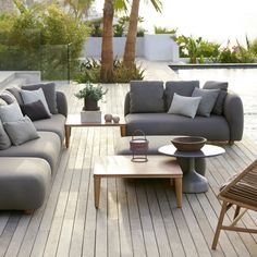 a living room filled with lots of furniture next to a swimming pool on top of a wooden floor