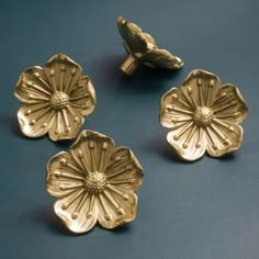 three gold flower shaped buttons on a blue surface