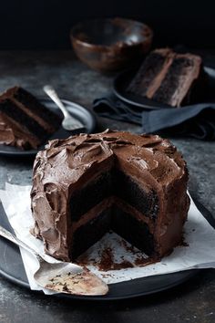 a chocolate cake sitting on top of a black plate next to a knife and fork