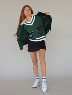 a young woman is posing for the camera wearing a green and white sweater with black letters on it