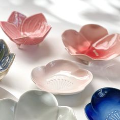 four different colored bowls sitting on top of a white tablecloth with flowers in them