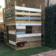 a child sitting on top of a wooden bunk bed in front of a brick building