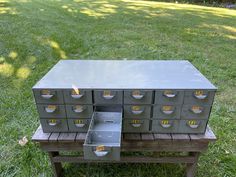 a metal filing cabinet sitting on top of a wooden bench next to a green field