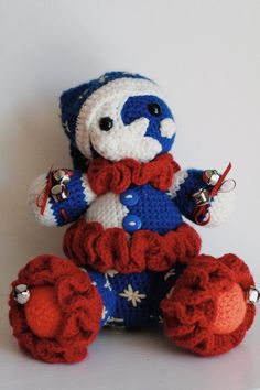 a crocheted teddy bear wearing a red, white and blue outfit sitting on top of a table