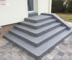 a set of stairs made out of granite sitting in front of a house