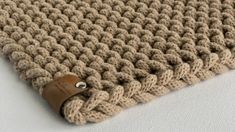 a close up of a knitted blanket with a leather button on the end,