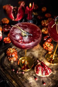 two cocktails with pomegranate garnishes on a metal tray