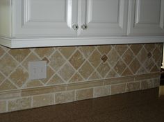 a tile backsplash in a kitchen with white cabinets