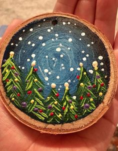 a hand holding a painted christmas ornament in it's left palm area