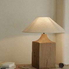 a lamp sitting on top of a wooden table next to a book and some books