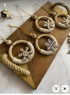 wooden hoops with snowflakes are hanging on a wood board next to pine cones