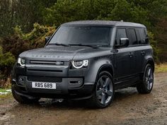 a black land rover parked in front of some trees