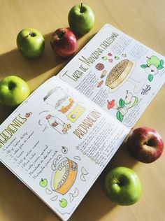 an open book with pictures of apples and other fruits on the table next to it