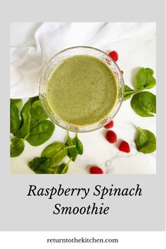 raspberry spinach smoothie in a glass on top of leaves and berries