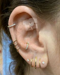 an ear with three different types of piercings on top of the ears and behind it is