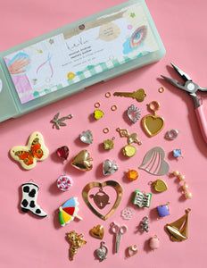 a pink table topped with lots of different types of pins and magnets next to a pair of scissors