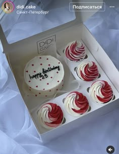 four cupcakes with white frosting and red sprinkles in a box