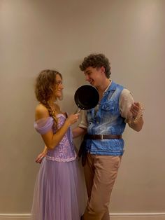 a man and woman dressed up as disney characters, one holding a frying pan