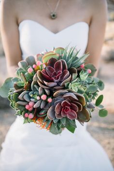 a bride holding a bouquet of succulents