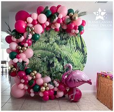 a flamingo balloon arch is decorated with pink, green and gold balloons for a tropical themed party