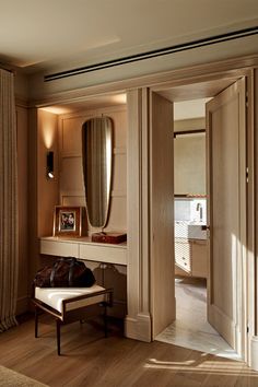 an open door leading to a dressing room with a bench and mirror on the wall