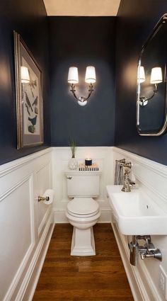 a white toilet sitting next to a sink in a bathroom on top of a wooden floor