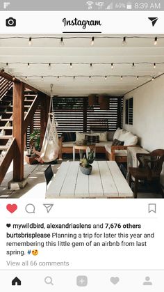 an outdoor living area with wooden furniture and string lights