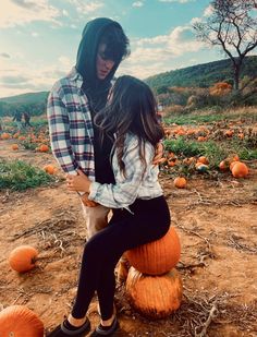 two people standing next to each other near pumpkins