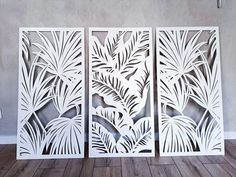 three panels with leaves cut out of them on a wooden floor in front of a wall