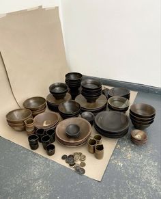 a table topped with lots of black and brown dishes next to a pile of coins