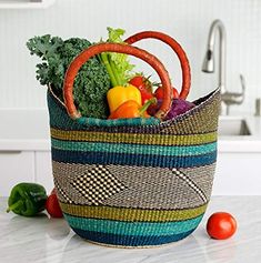 a basket filled with vegetables sitting on top of a kitchen counter next to tomatoes and broccoli