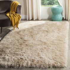 a living room area with a chair, rug and window in front of the couch