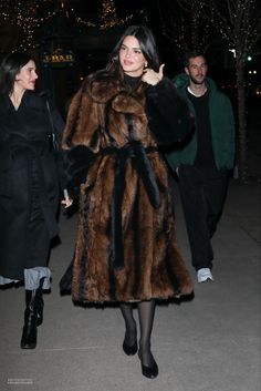 a woman in a fur coat is walking down the street