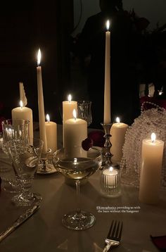 candles are lit on a table with silverware