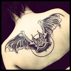 the back of a woman's shoulder with a bat tattoo on her upper arm