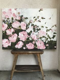 an oil painting of pink roses on a white wall with a wooden stool in the foreground