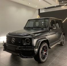 a black mercedes g - class is parked in a showroom