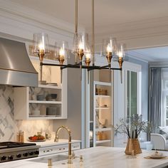 a kitchen with marble counter tops and gold accents on the chandelier over the island