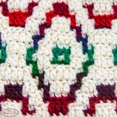 a crocheted blanket with green, red and white squares