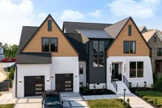 a car is parked in front of a two - story house with black shutters