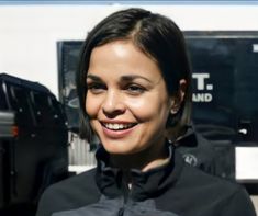 a woman standing in front of a truck smiling at the camera