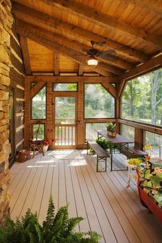 a covered porch with tables and benches on it's sides, surrounded by greenery