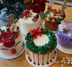 four decorated cakes sitting on top of a table next to a christmas tree and decorations