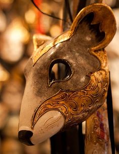 an animal mask is hanging on the wall in front of some other masks and decorations