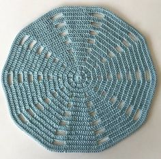 a blue crocheted placemat on a white surface with holes in the middle