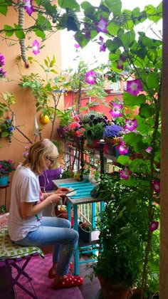 a woman sitting on top of a chair in front of potted plants and flowers