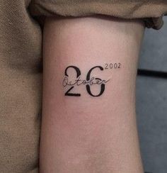 a woman's wrist tattoo with the number twenty six in black on her left arm