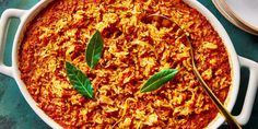 a large casserole dish filled with rice and meat, garnished with green leaves