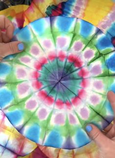 two hands are holding a colorful paper plate